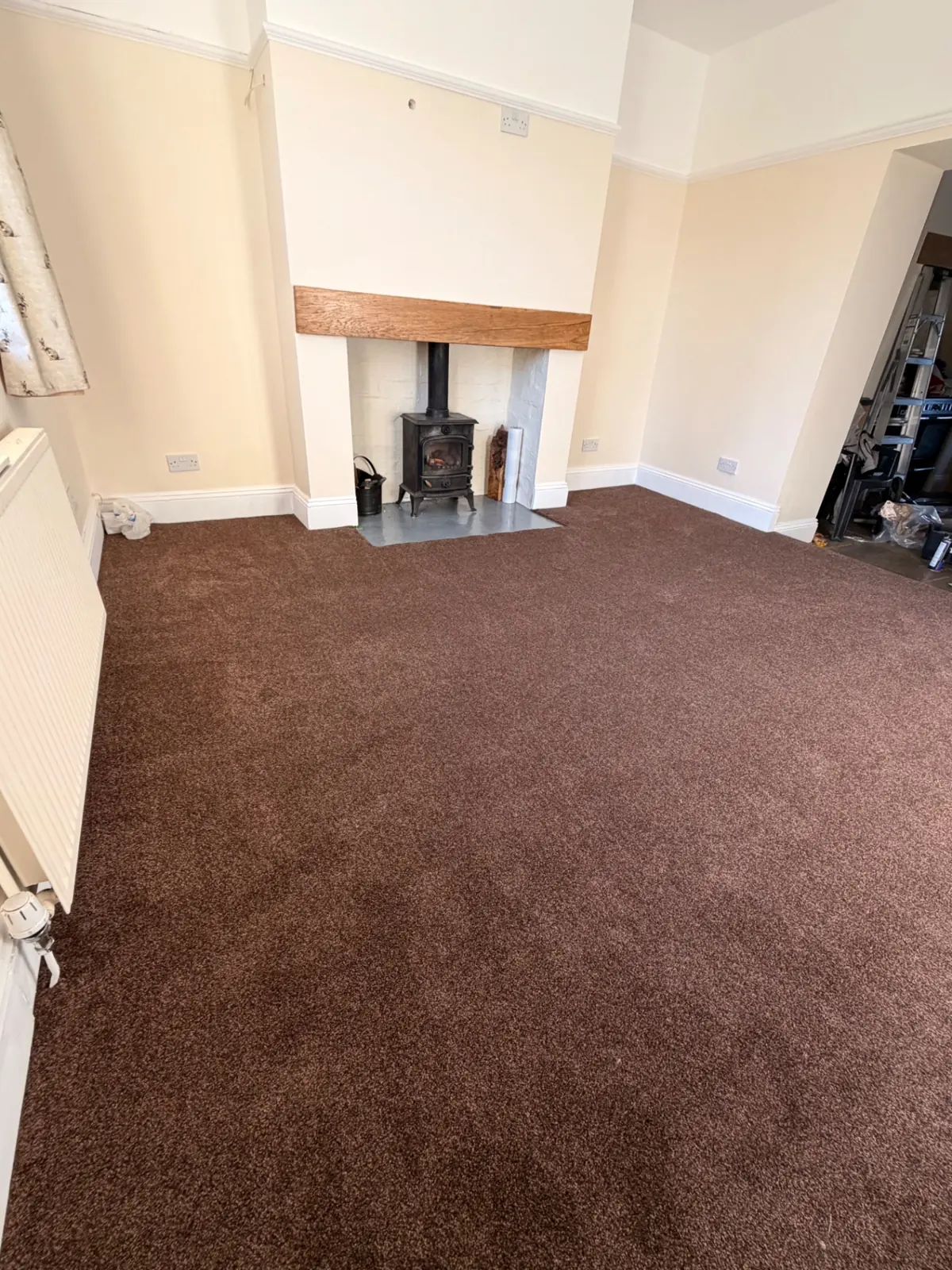 Brown dining room carpet fitted beside a log burner in Bishop Auckland